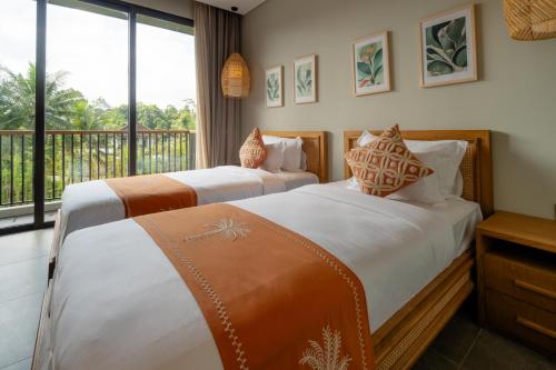 two beds in a room with a balcony at Renjana Villas in Ubud