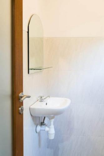 a bathroom with a white sink and a mirror at Uluwatu Hill House in Uluwatu