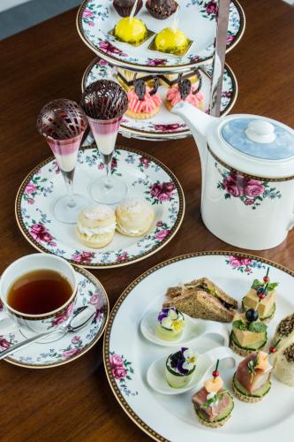 a table with plates of desserts and a cup of tea at Langham Place Guangzhou - Walking distance to Canton Fair in Guangzhou