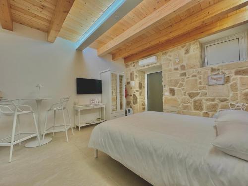 a bedroom with a bed and a table and a tv at Amurusa Room in Noto