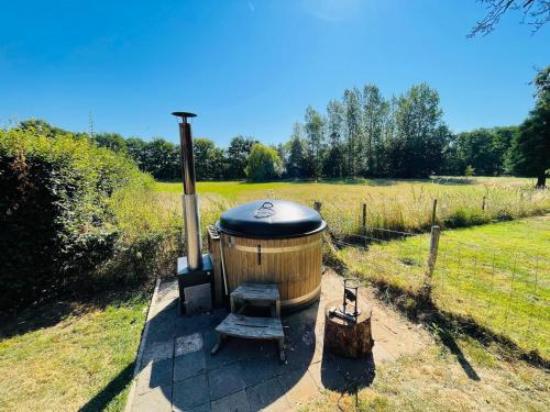 a hot tub with a stove in a field at Coachman's House near Roermond with Garden in Sint Odiliënberg