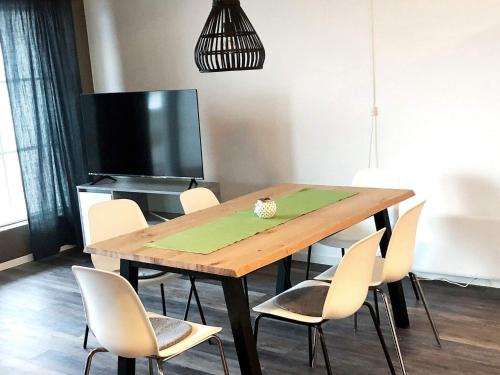 a dining room table with white chairs and a television at 6 person holiday home in Kverva in Dyrvik