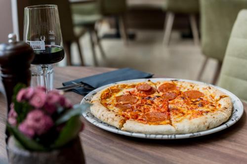 a pepperoni pizza on a table next to a glass of wine at Platzhirsch Living in Kelsterbach