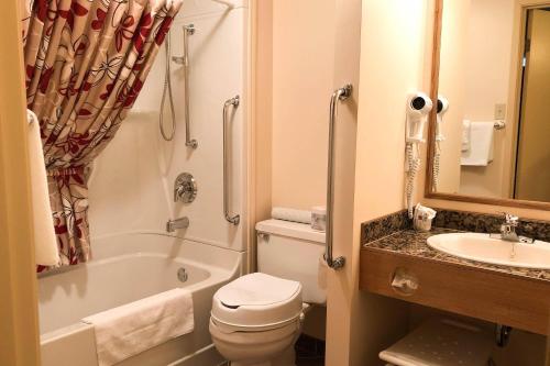 a bathroom with a toilet and a tub and a sink at Rodeway Inn in Gaspé