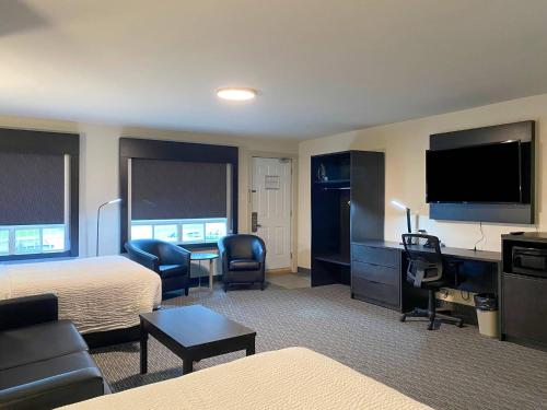 a hotel room with a bedroom with a bed and a television at Rodeway Inn in Gaspé