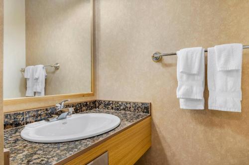 a bathroom with a sink and a mirror and towels at Rodeway Inn in Gaspé