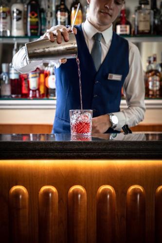 a bartender making a drink at a bar at Hotel Ercolini & Savi in Montecatini Terme