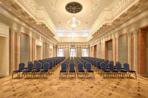 an empty room with blue chairs and a chandelier at Hotel Saski Krakow Curio Collection by Hilton in Kraków