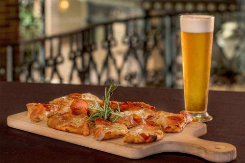 a wooden cutting board with a pizza and a glass of beer at Courtland Grand Hotel, Trademark Collection by Wyndham former Sheraton Atlanta in Atlanta