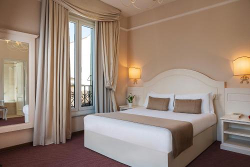 a bedroom with a white bed and a large window at Hotel Ercolini & Savi in Montecatini Terme