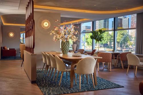 a dining room with a table and chairs with a vase of flowers at DoubleTree by Hilton Rotterdam Centre in Rotterdam