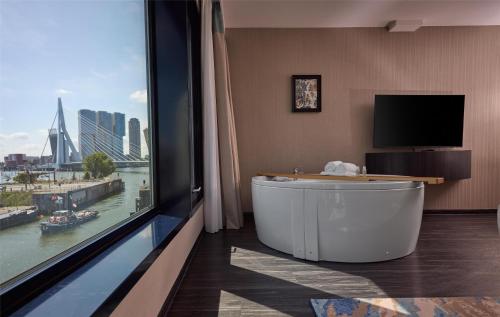 a bath tub in a room with a large window at Haven Hotel Rotterdam, Curio Collection by Hilton in Rotterdam
