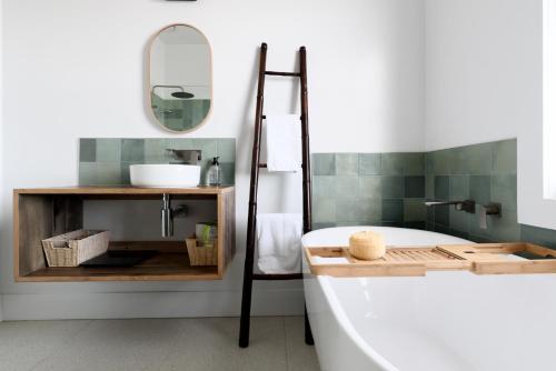 a bathroom with a tub and a sink and a mirror at Cosy Getaway with outdoor spaces in Launceston
