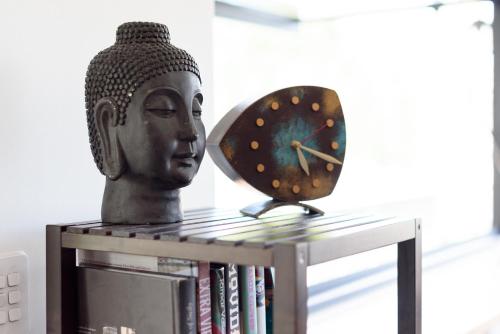 a clock and a statue sitting on a book shelf at Cosy Getaway with outdoor spaces in Launceston