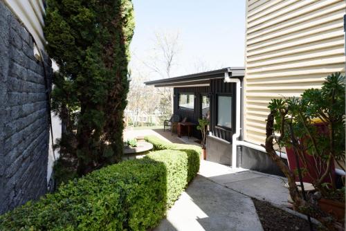 a house with green hedges next to a building at Cosy Getaway with outdoor spaces in Launceston