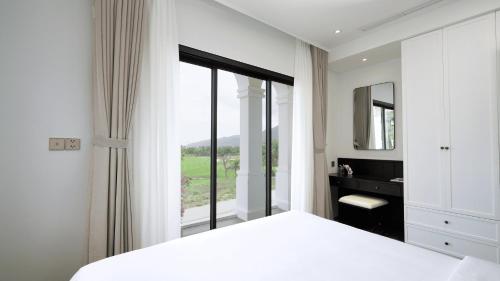 a bedroom with a white bed and a large window at Swiss-Belvillas Solavita Binh Tien in Binh Tien