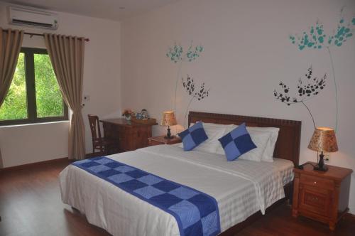 a bedroom with a bed with blue and white sheets at Tra Que Riverside Homestay in Hoi An