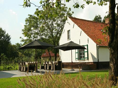 two black umbrellas in front of a white house at Beernem Farmhouse with Pool in Beernem