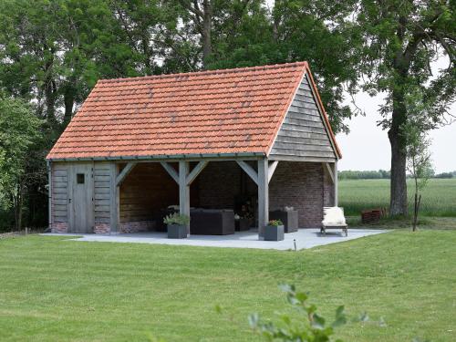 a small building with a red roof in a field at Farmhouse in Zuidzande near Cadzand Beach in Zuidzande