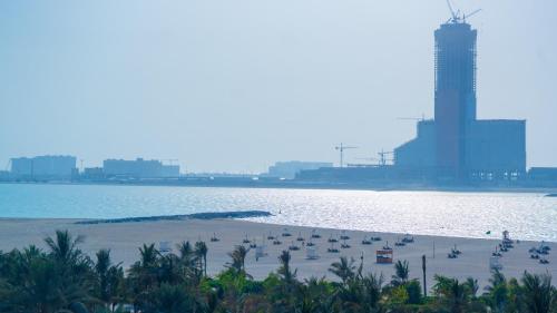 a beach with a bunch of people sitting on the sand at The Grand Hamra Stay by Hala Holiday Homes in Ras al Khaimah