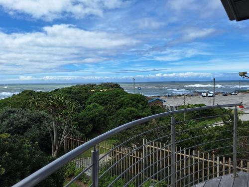a balcony with a view of the ocean and a beach at Seaside Beach House with Pool & Invertor in Port Alfred