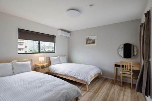 a bedroom with two beds and a mirror and a window at Fukuoka Airport 7 in Shime