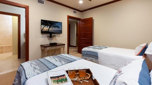 a bedroom with two beds and a tv on the wall at COCONUT TELEGRAPH Rejuvenating 3BR Villages Home Near Recreation Center in Waikoloa