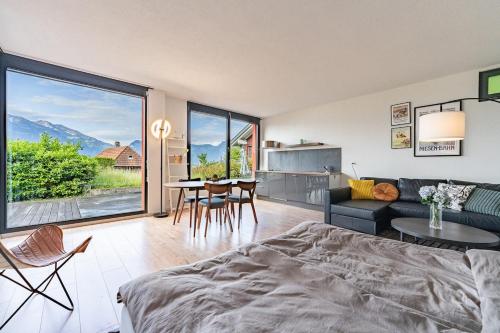 a living room with a couch and a table at Light-filled studio with panoramic views in Oberhofen am Thunersee