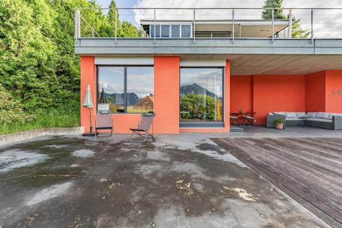 a house with orange walls and a patio at Light-filled studio with panoramic views in Oberhofen am Thunersee