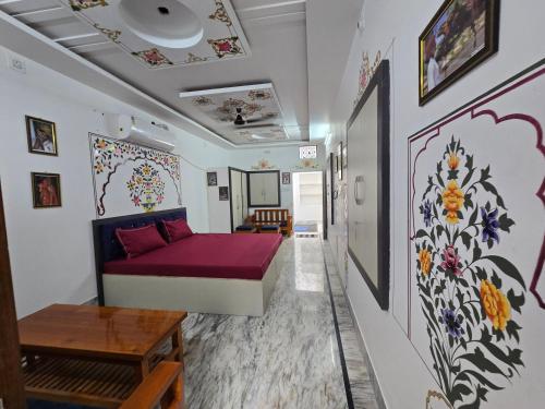 a room with a bed and a living room with paintings on the walls at little Princess Guest House in Bikaner