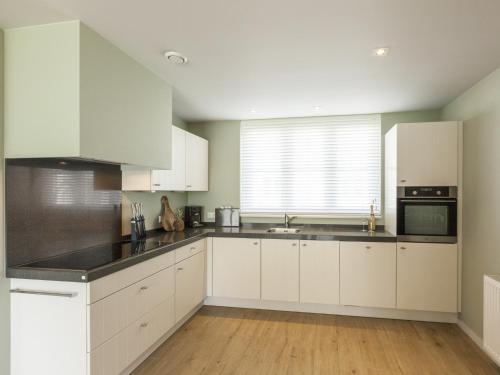 a white kitchen with white cabinets and a window at Villa in Cadzand near Beach & Dunes in Cadzand