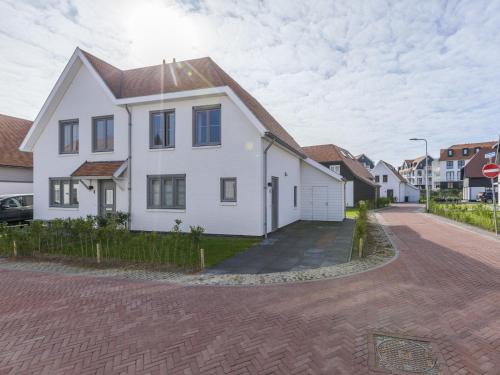 a white house with a brown roof on a street at Villa in Cadzand near Beach & Dunes in Cadzand