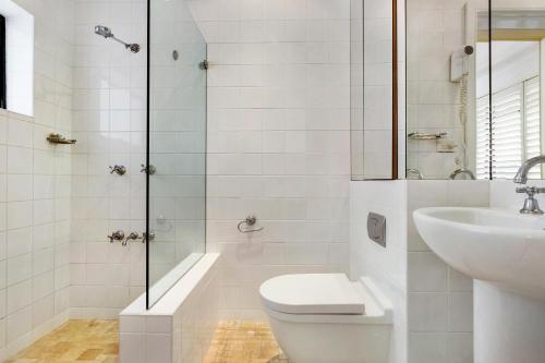 a white bathroom with a toilet and a sink at Ballantyne at Mosman Apartments in Sydney