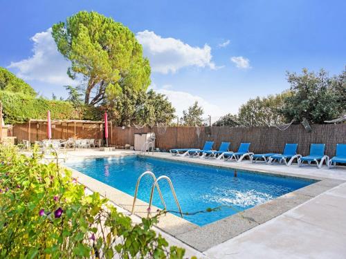 a swimming pool with blue chairs and a fence at Tranquil Garden Hideaway in Galapagar