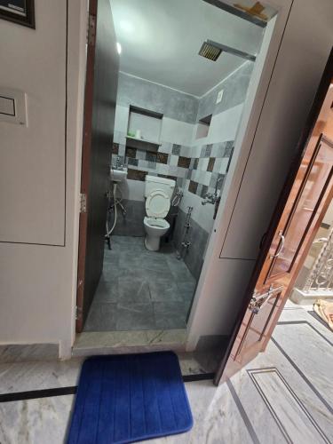 a bathroom with a toilet and a blue mat at little Princess Guest House in Bikaner