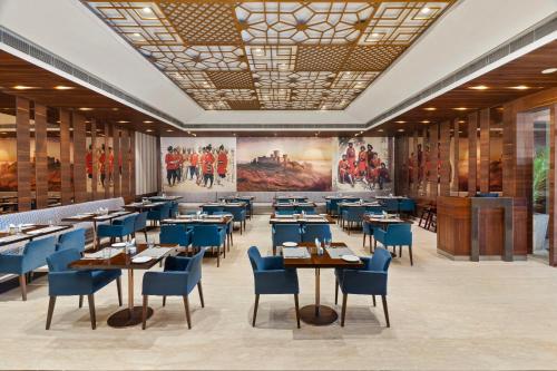 Un comedor con mesas y sillas azules y cuadros. en Country Inn Premier Amritsar - 10 min drive from Golden Temple, en Amritsar