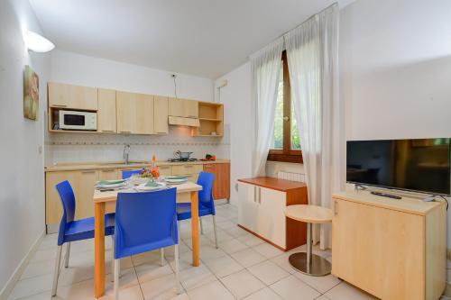 a kitchen and dining room with a table and blue chairs at Budget Village Apartments - Porto Letizia in Porlezza