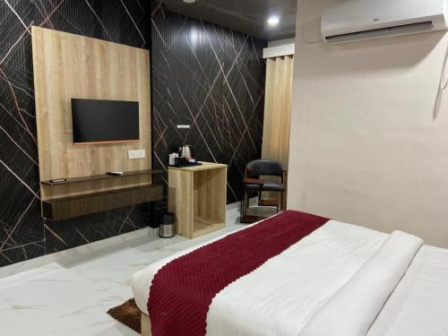 a bedroom with a bed and a tv in a room at Hotel Ganga Pearl in Rishīkesh