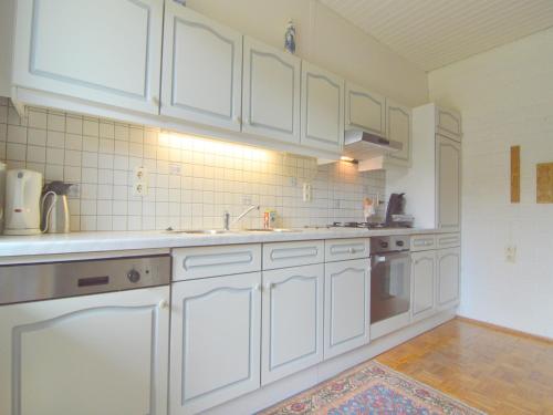 a kitchen with white cabinets and a sink at Holiday Home in Sittard with Pool in Spaubeek