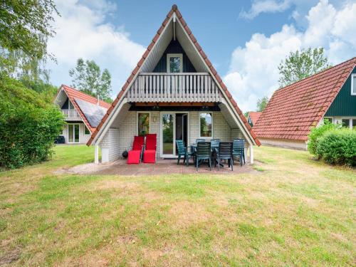 a house with a thatched roof with tables and chairs at Holiday home in Gramsbergen in Gramsbergen