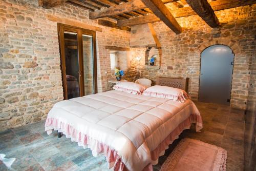 ein Schlafzimmer mit einem großen Bett in einer Ziegelwand in der Unterkunft Vecchio Forno Only Adult, Luxury, History, Comfort in Fiorenzuola di Focara