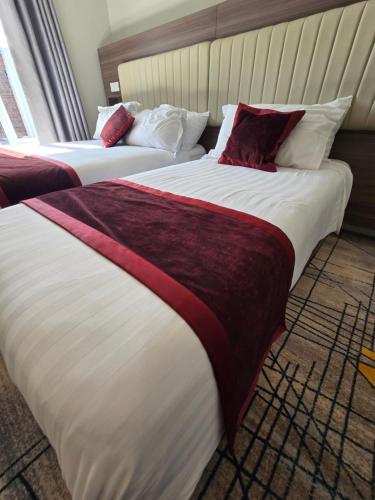 two beds in a hotel room with white and red sheets at KGT House in Dublin
