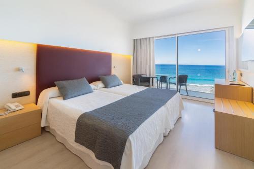 a bedroom with a large bed with a view of the ocean at CM Playa del Moro in Cala Millor