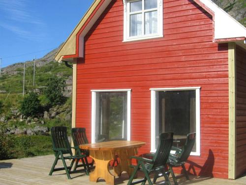 a red house with chairs and a table in front of it at 6 person holiday home in Bøstad-By Traum in Tangstad