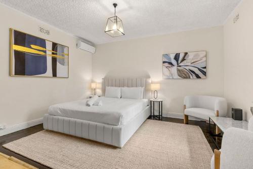 a white bedroom with a white bed and a chair at Millers Point Retreat 5 Min Walk to Barangaroo in Sydney