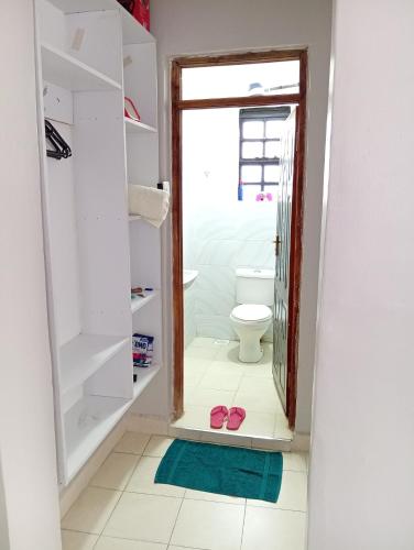 a bathroom with a toilet and a pair of flip flops at Wellys Serenity Haven in Kitengela 