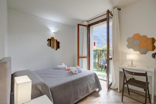 a bedroom with a bed and a desk and a window at Budget Village Apartments - Porto Letizia in Porlezza