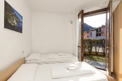 a bedroom with two beds and a large window at Budget Village Apartments - Porto Letizia in Porlezza