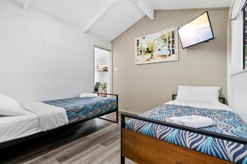 a bedroom with two beds and a flat screen tv at Ingenia Holidays Kinka Beach Yeppoon in Kinka