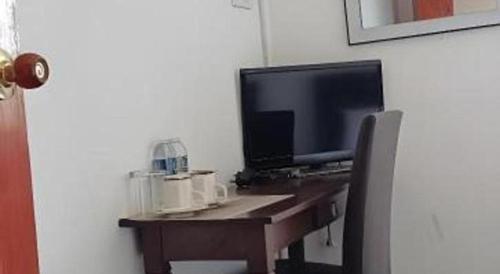 a desk with a television and a desk with a chair at OYO 90785 Pandan Hotel in Kota Kinabalu